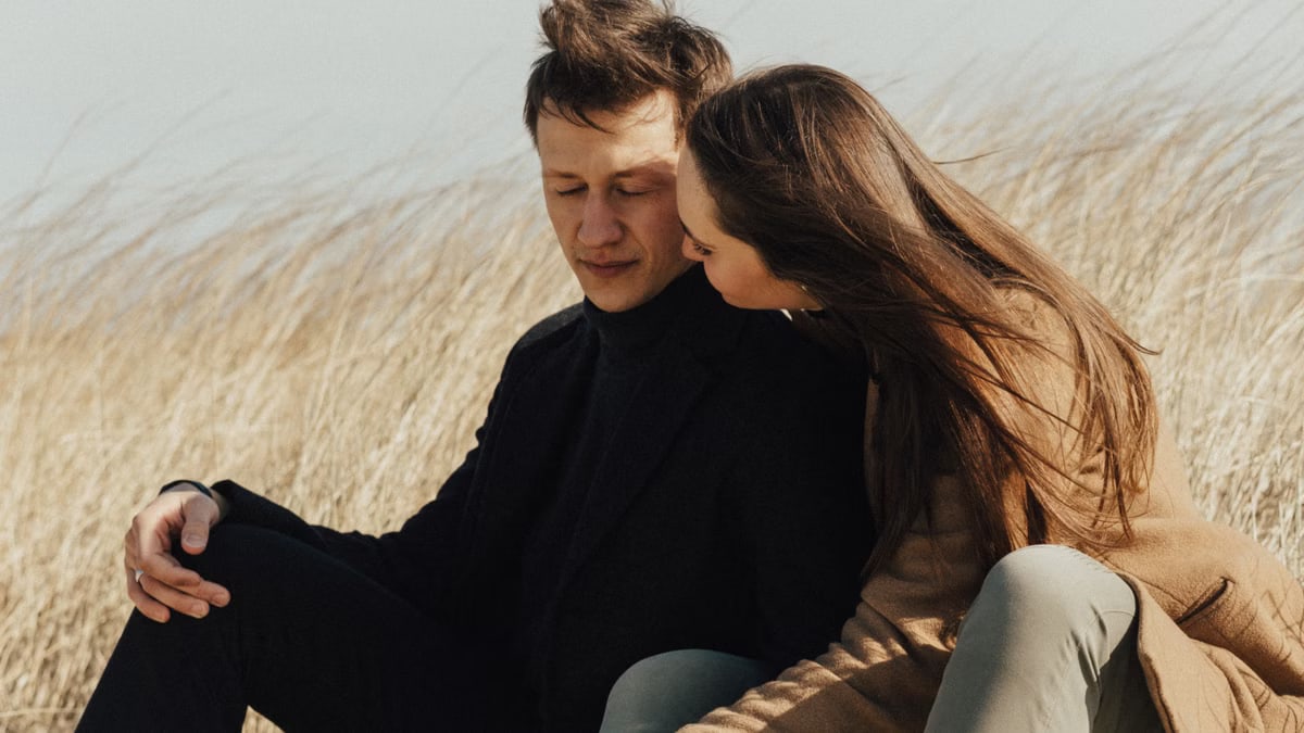 A couple sitting closely in an open field, showcasing love and affection.